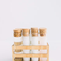 organic-spa-product-test-tubes-arranged-wooden-container-white-surface